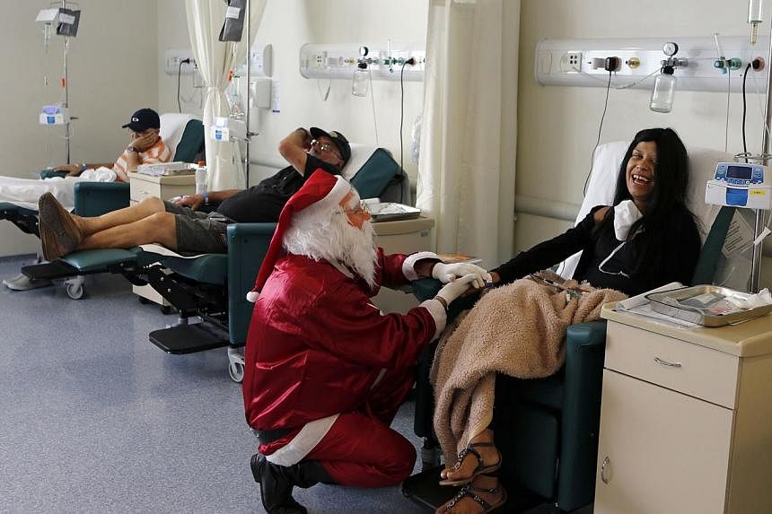 A man dressed as Santa Claus talks to a cancer patient undergoing chemotherapy in the Cancer Institute in Sao Paulo on Dec 19, 2014. In Singapore, MediShield Life, which would have come into effect by then, will greatly increase coverage for cancer c