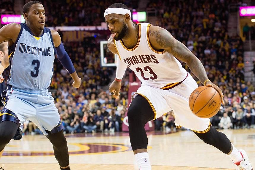 LeBron James (right) of the Cleveland Cavaliers drives past Jordan Adams of the Memphis Grizzlies during the second half at Quicken Loans Arena on Dec 21, 2014 in Cleveland, Ohio. -- PHOTO: AFP