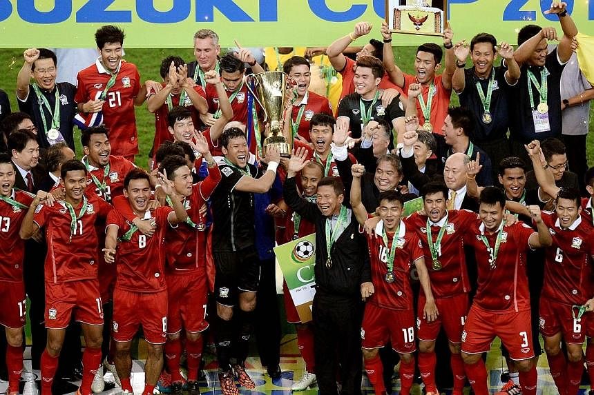 Thailand football team players celebrate with the trophy after defeating Malaysia during their AFF Suzuki Cup 2014 second-leg Final football match at the Bukit Jalil Stadium in Kuala Lumpur on Dec 20, 2014. -- PHOTO: AFP