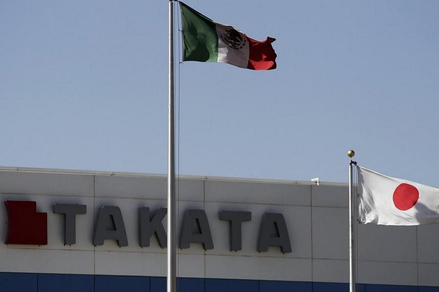 The Mexican and the Japanese national flags are seen outside the Takata plant in Monclova in this April 11, 2013 file photo.&nbsp;The president of embattled Japanese auto parts maker Takata stepped down Wednesday over an airbag scandal linked to at l
