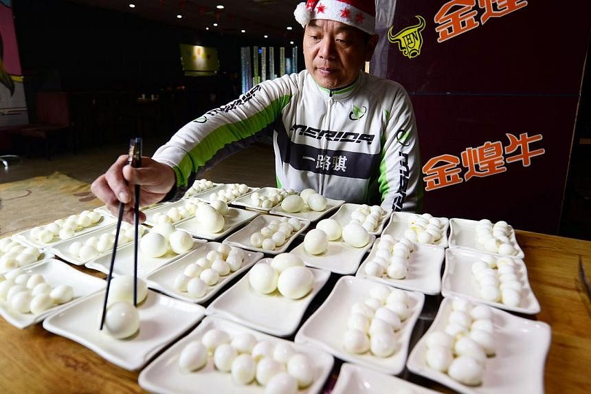 Chinese competitive eater Pan Yizhong picking up an egg at a buffet restaurant in Changsha, in central China's Hunan province on Dec 23, 2014. -- PHOTO: AFP