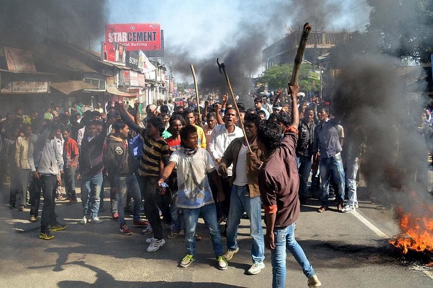 Activists of the Assam Tea Tribes Student Association (ATTSA) shout slogans as they block the road with burning tyres during a protest against attacks on villagers by militants in four different locations, at Biswanath Chariali in the Sonitpur distri
