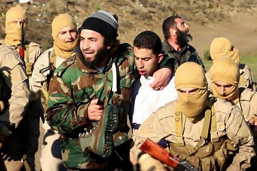 A still image released by the Islamic State group's branch in Raqa on militant websites on Dec 24, 2014, purportedly shows a Jordanian pilot (centre) captured by ISIS fighters. -- PHOTO: AFP