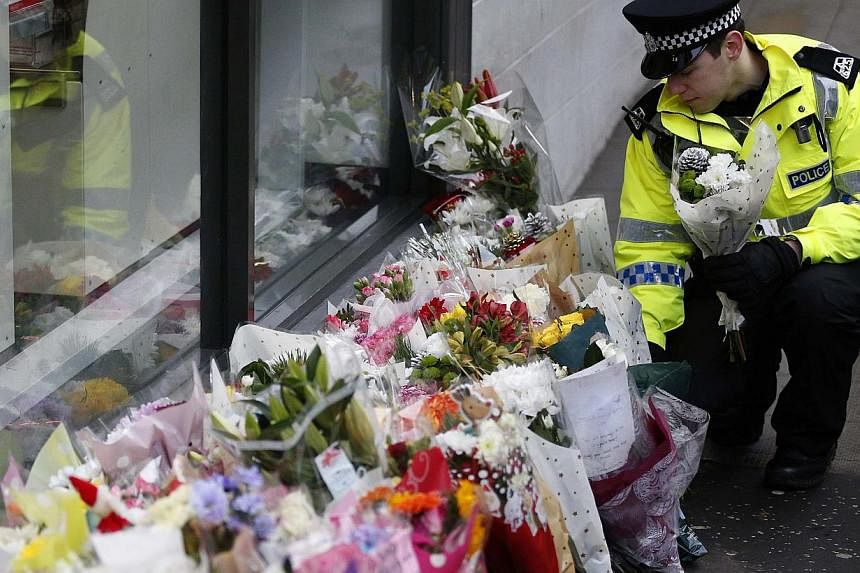 A police officer places flowers from a member of the public near the scene where a refuse truck crashed into pedestrians in George Square, Glasgow, Scotland Dec 23, 2014. -- PHOTO: REUTERS