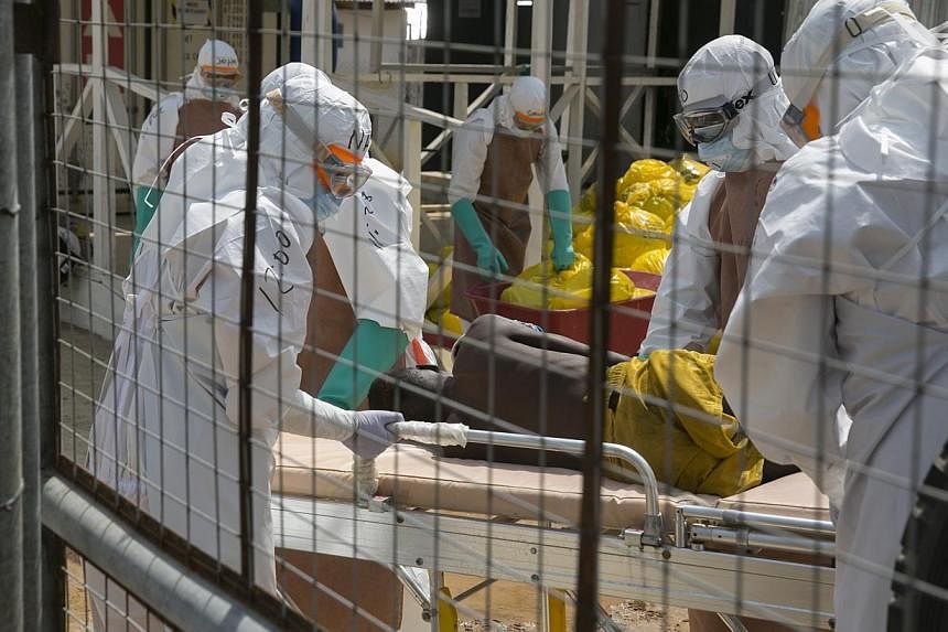 Health workers lift a newly admitted Ebola patient onto a wheeled stretcher in the Kerry town Ebola treatment centre outside Freetownon Dec 22, 2014. -- PHOTO: REUTERS