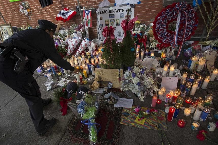 A New York City police officer lights a candle as she visits a makeshift memorial at the site where two police officers were fatally shot in the Brooklyn borough of New York, Dec 23, 2014.&nbsp;Protesters who have rallied for weeks over excessive use