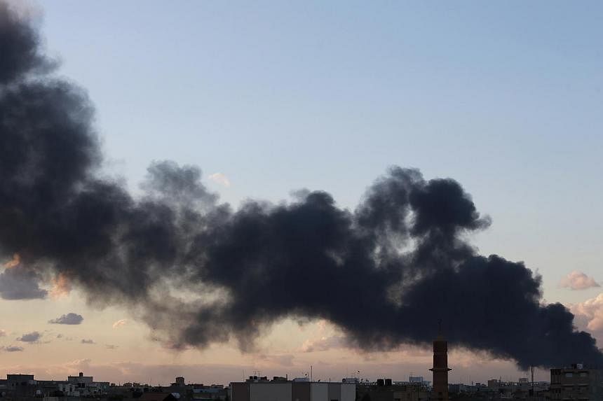 Black smoke billows in the sky above areas where clashes are taking place between pro-government forces, who are backed by the locals, and the Shura Council of Libyan Revolutionaries, an alliance of former anti-Gaddafi rebels, who have joined forces 