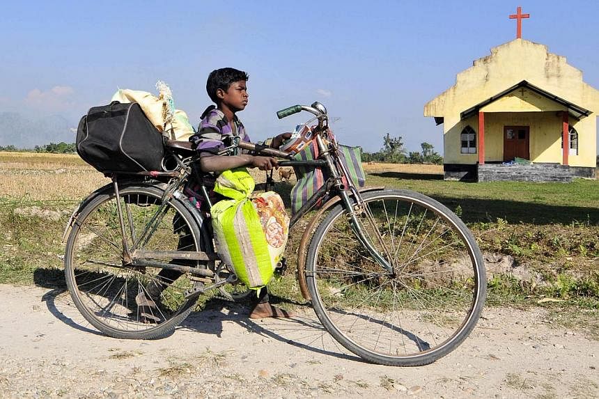 A boy transports his belongings on a bicycle as he moves to a safer place after ethnic clashes in Tenganala village, in Sonitpur district in the northeastern Indian state of Assam on Dec 24, 2014. -- PHOTO: REUTERS&nbsp;