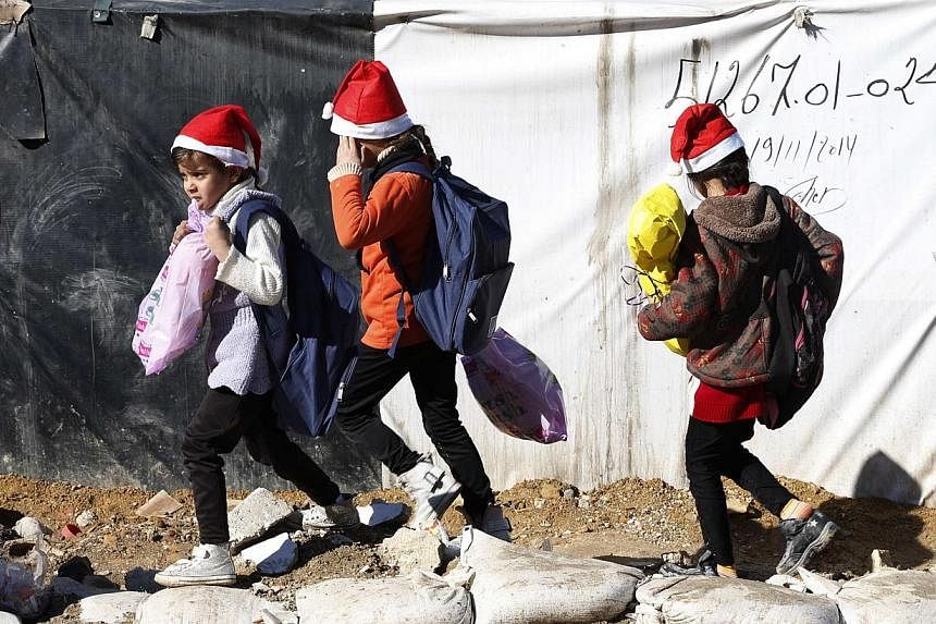 Syrian refugee girls hold their Christmas gifts from SAWA, a non-governmental organisation, in Bar-Elias in the Bekaa valley on Dec 24, 2014. -- PHOTO: REUTERS&nbsp;