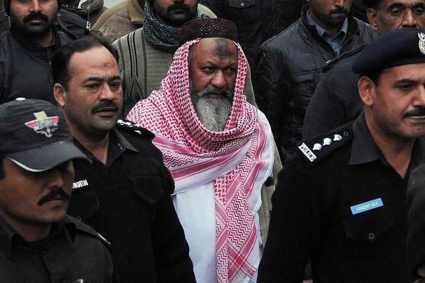 This photograph taken on Dec 22, 2014, shows Pakistani police escorting the head of banned Lashkar-e-Jhangvi (LeJ) Malik Ishaq as he arrives at the high court in Lahore. -- PHOTO: AFP