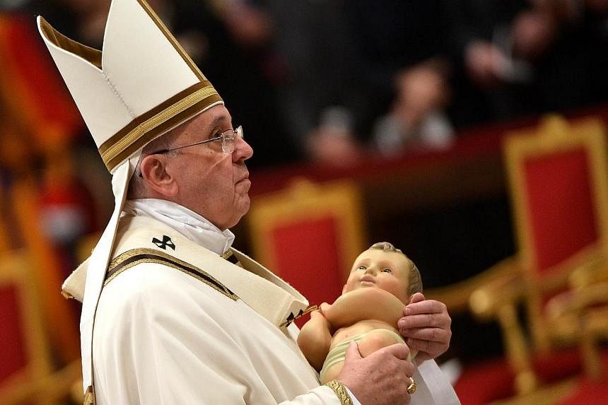 Pope Francis leaves with the unveiled baby Jesus after the Christmas Eve mass at St Peter's Basilica to mark the nativity of Jesus Christ, on Dec 24, 2014 at the Vatican.&nbsp;Pope Francis will celebrate Christmas on Thursday by sending the world's 1