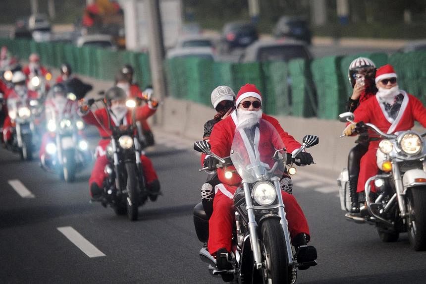 Owners of Harley-Davidson motorcycles wearing Santa Claus costumes ride along a street to give presents to elders at a nursing home during a promotional event celebrating Christmas in Guangzhou. A Chinese city has banned schools from holding Christma