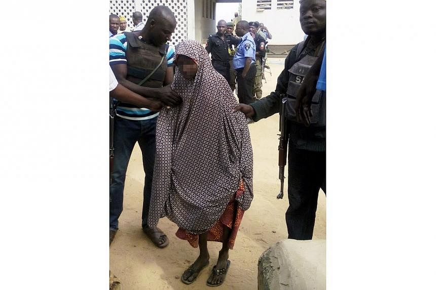 Zahra'u Babangida (centre), a 14-year-old Nigerian girl arrested with explosives strapped to her body in Kano on Dec 10 following a double suicide bombing in a market that killed 10 people, is assisted by police at the Kano state police headquarters 