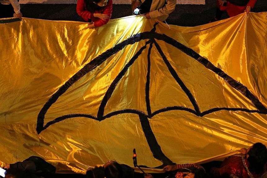 Protesters carry a long yellow banner during a march with an umbrella, a recent symbol of Hong Kong's democracy movement, painted on it during a march to mark Christmas Eve on Dec 24, 2014. -- PHOTO: AFP&nbsp;
