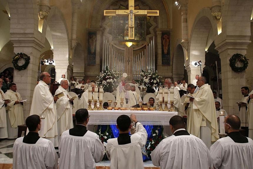 Christian priests hold a Christmas Midnight Mass at the Church of the Nativity in the West Bank town of Bethlehem on Dec 25, 2014. -- PHOTO: REUTERS&nbsp;