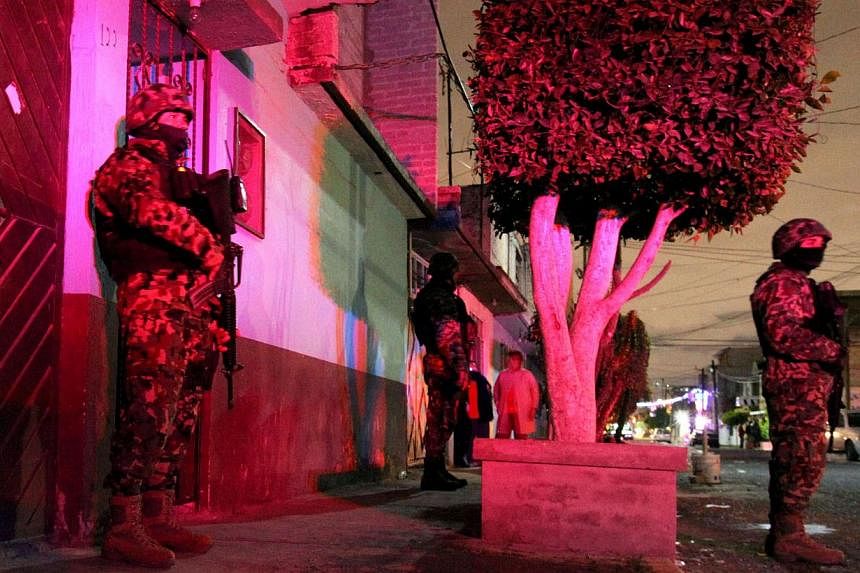 Members of the Mexican Army remain outside the house where a family - including six children - was killed, in the municipality of Ecatepec, state of Mexico, on Dec 24, 2014. A Mexican soldier is suspected of strangling his six children and beating hi