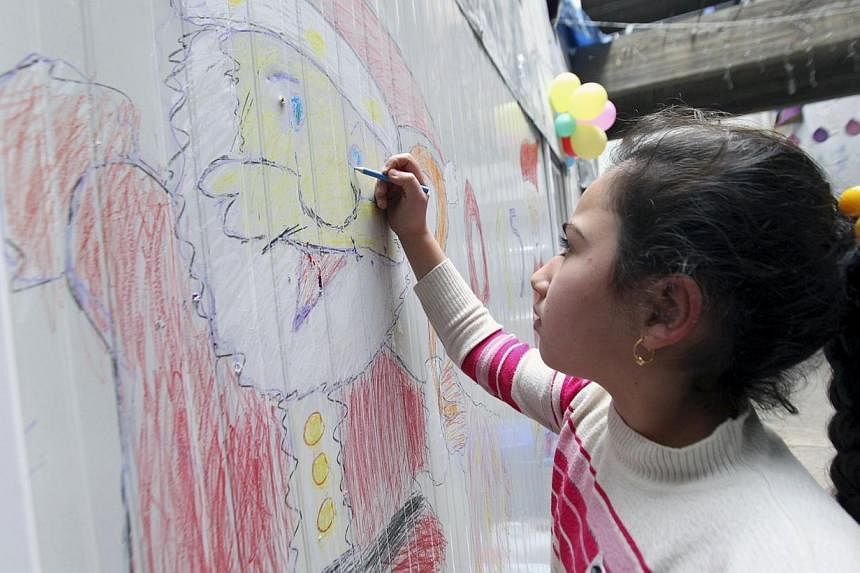 A displaced Iraqi Christian girl who fled from Islamic State militants in Mosul, draws a picture of Santa Claus at a mall still under construction, used as a refugee camp in Arbil Dec 24, 2014. -- PHOTO: REUTERS