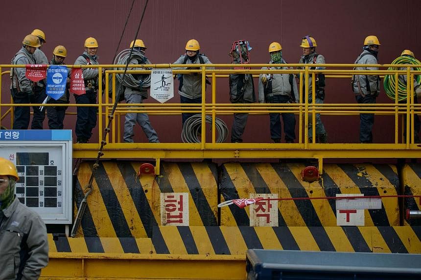 Workers queueing to enter an under-construction container ship at the Daewoo DSME shipyard in Okpo, South Korea. South Korea has finalised details on a plan to tax "excessive" cash reserves held by companies. -- PHOTO: AFP