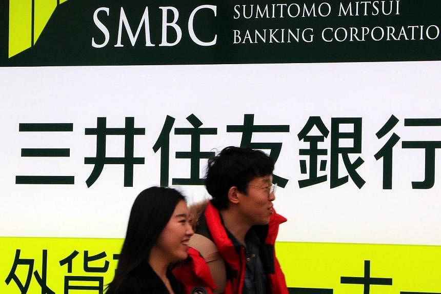 Pedestrians passing by a branch of the Sumitomo Mitsui bank in Tokyo on Dec 25, 2014. Sumitomo Mitsui Financial Group will buy the Japanese retail business of US banking giant Citigroup. -- PHOTO: AFP
