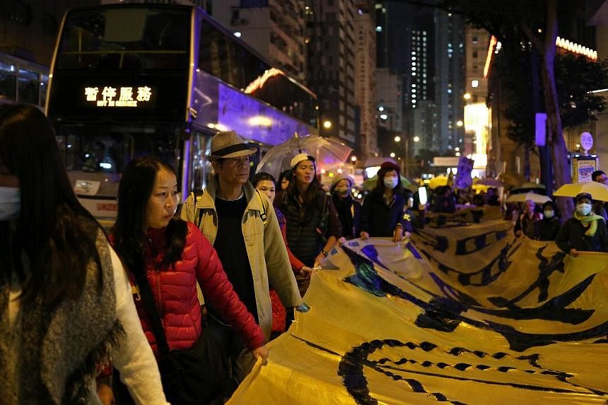 Protesters carry a long banner and yellow umbrellas -- the recent symbol of Hong Kong's democracy movement -- during a march to mark Christmas Eve on Dec 24, 2014. Chinese Premier Li Keqiang on Friday heaped praise on the Hong Kong authorities as he 