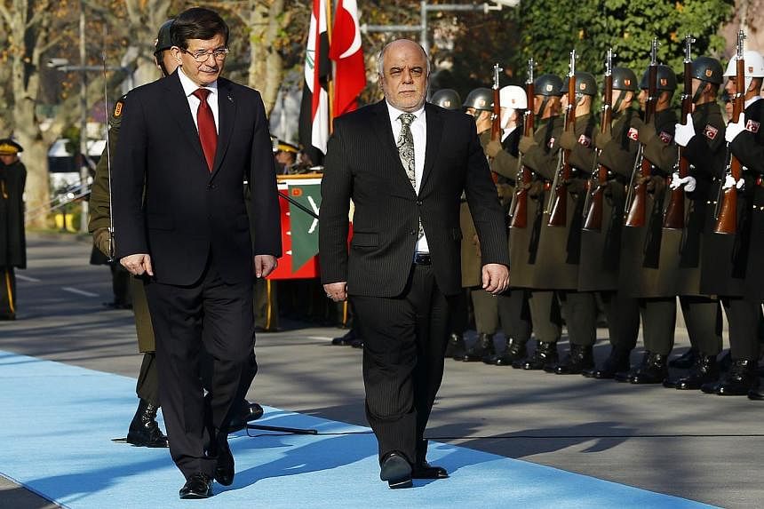 Turkey's Prime Minister Ahmet Davutoglu (left) and Iraqi Prime Minister Haider al-Abadi review a guard of honour during a welcoming ceremony in Ankara Dec 25, 2014. Iraq and Turkey on Thursday pledged to join forces to fight Islamic State insurgents 