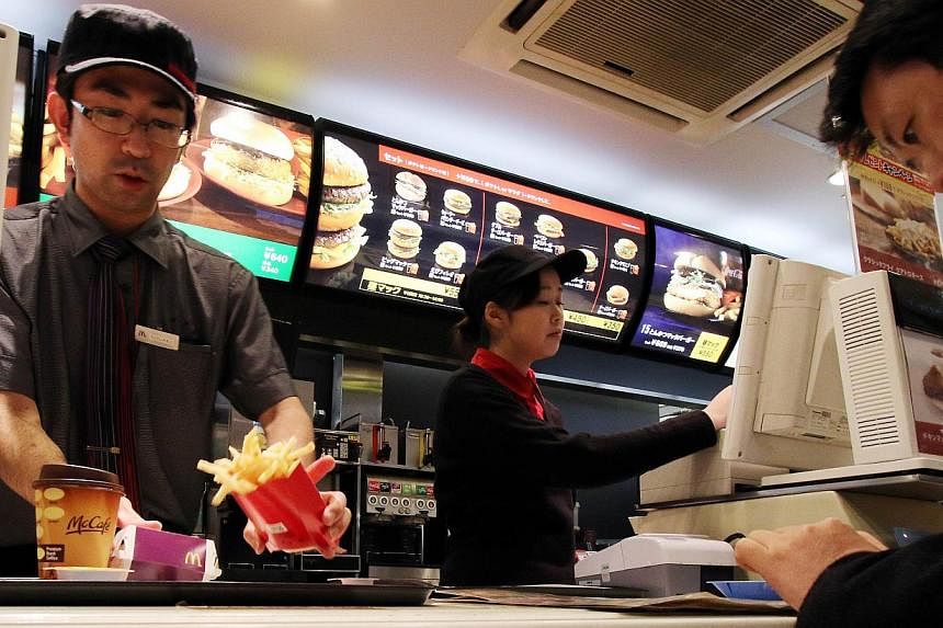 An employee serves french fries to a customer at a McDonald's restaurant in Tokyo on Dec 16, 2014. -- PHOTO: AFP