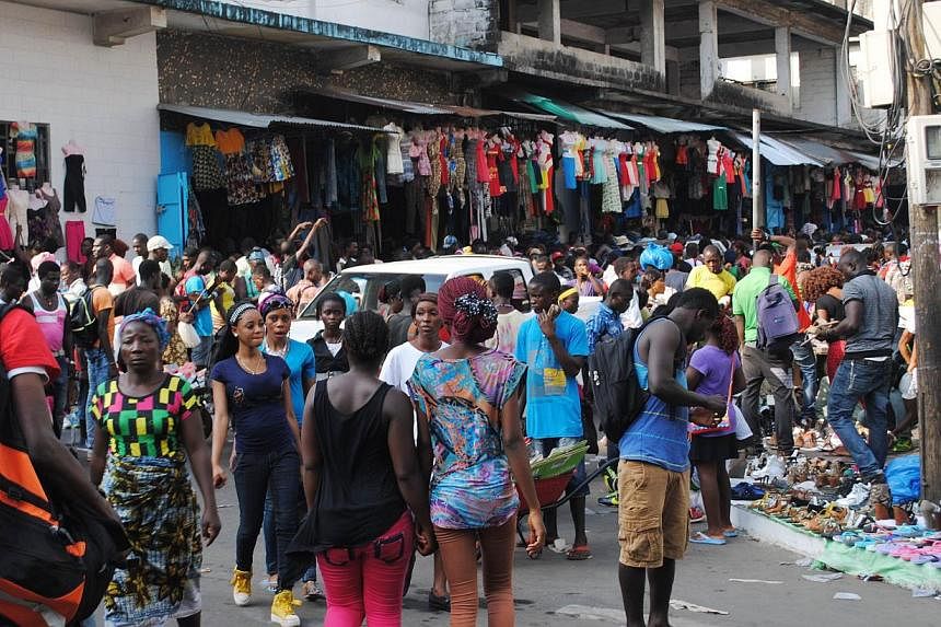 People walk in a market on Dec 24, 2014 in Monrovia.&nbsp;The Ebola epidemic has cast a dark shadow over Christmas this year in Liberia, where small businesses are especially feeling the pinch. -- PHOTO: AFP