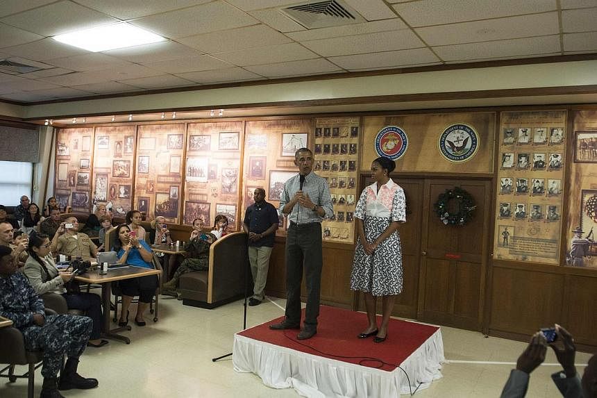 US President Barack Obama addresses troops on Christmas Day at Marine Corps Base Hawaii in Kaneohe on Dec 25, 2014 as First Lady Michelle Obama looks on. -- PHOTO: AFP