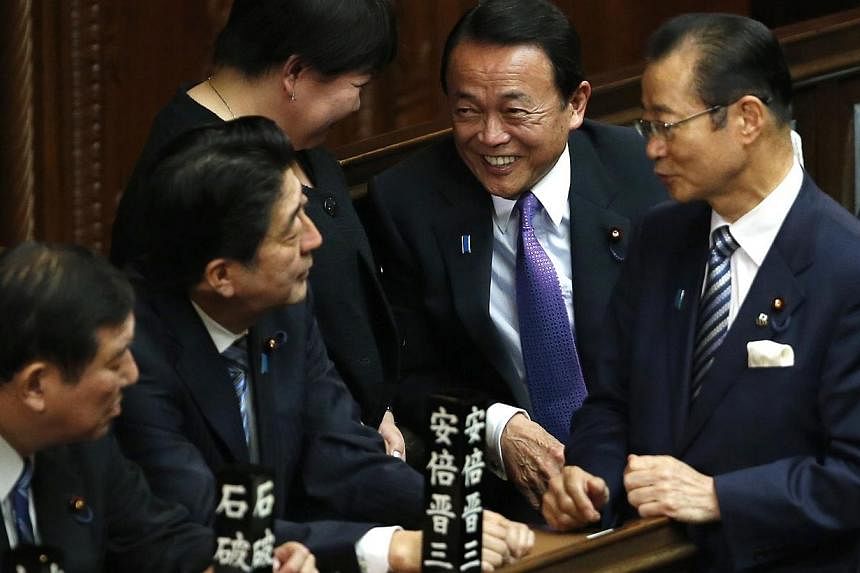 Japan's Finance Minister Taro Aso (second from right) talks with Japan's Prime Minister Shinzo Abe (second from left) and ruling Liberal Democratic Party lawmaker Shigeru Ishiba (left) at the Lower House of the Parliament in Tokyo Dec 24, 2014. Japan