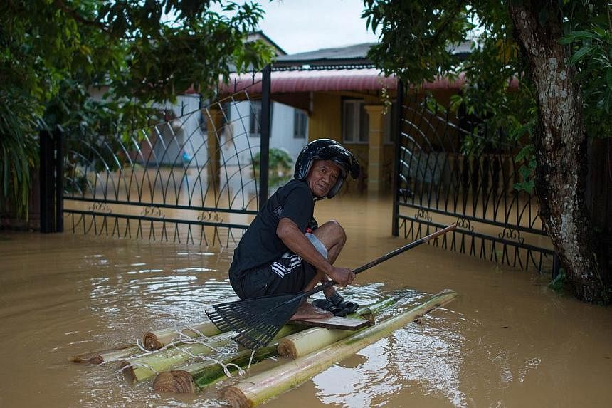 A man making his way to his house that has submerged in floodwaters in Pengkalan Chepa, near Kota Bharu, Kelantan, on Dec 27, 2014. &nbsp;Negeri Sembilan is the 8th Malaysian state affected by floods. -- PHOTO: AFP