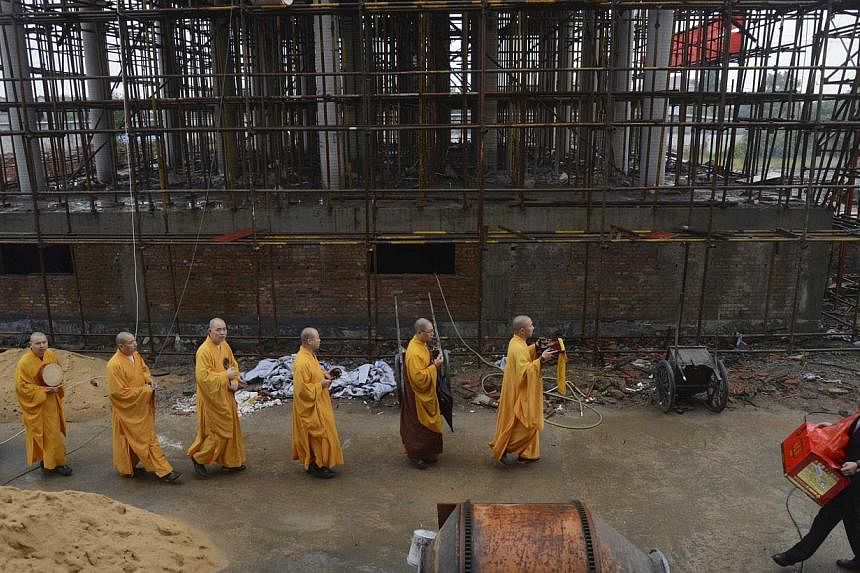 Monks chant sutras for a half-way built Buddhist temple donated by a property developer in Jiaxing, Zhejiang province on Oct 31, 2014. -- PHOTO: REUTERS