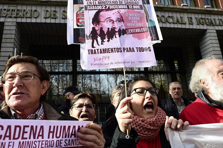 Hepatitis C sufferers and supporters hold placards during a demonstration outside Spain's health ministry on Dec 27, 2014, complaining that they are being denied access to a new drug that could cure them of the deadly liver disease. -- PHOTO: AFP
