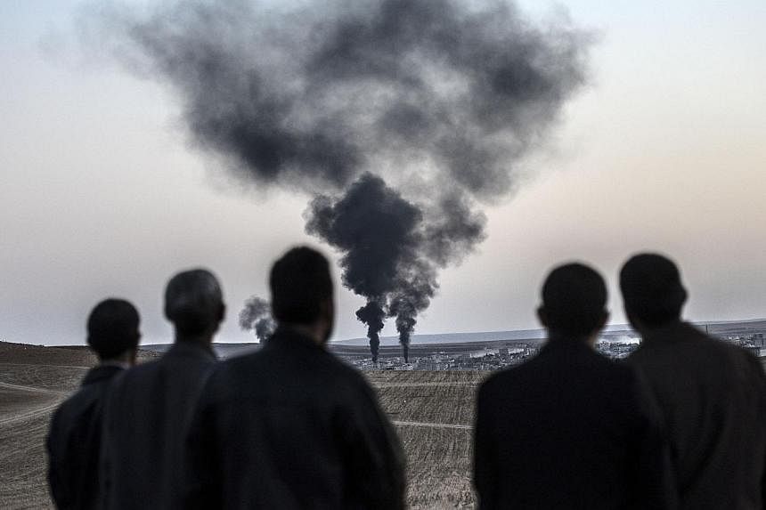 People watch as smokes rises from the town of Kobane, also known as Ain al-Arab, on Oct 26, 2014, at the Turkish border near the southeastern village of Mursitpinar, Sanliurfa province. -- PHOTO: AFP
