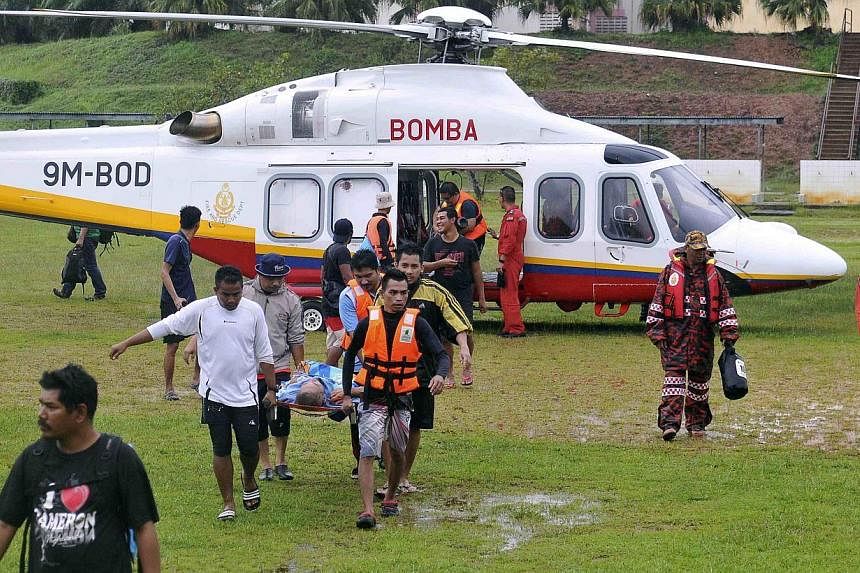 Volunteers carry a man on a stretcher out of a helicopter during a mission to evacuate elderly people from the National Park in Kuala Tahan, to Jerantut, Pahang on Dec 24, 2014. -- PHOTO: REUTERS&nbsp;