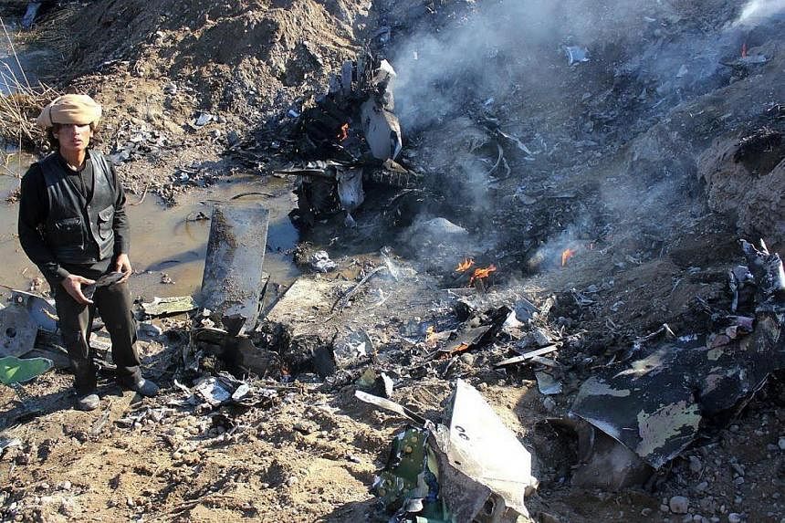 A picture taken on Dec 24, 2014 reportedly shows an Islamic State group fighter collecting pieces from the remains of a Jordanian warplane from the US led coalition after it came down in Syria's Raqa region. -- PHOTO: AFP