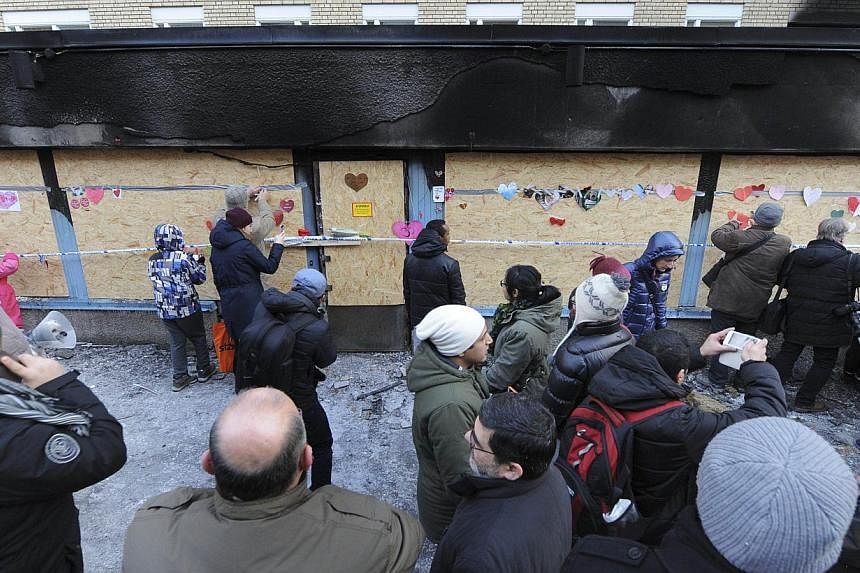 People leave flowers and other messages of good will at the scene of a destroyed mosque the day after an arson attack on Dec 26, 2014 in Eskilstuna, central Sweden. -- PHOTO: AFP