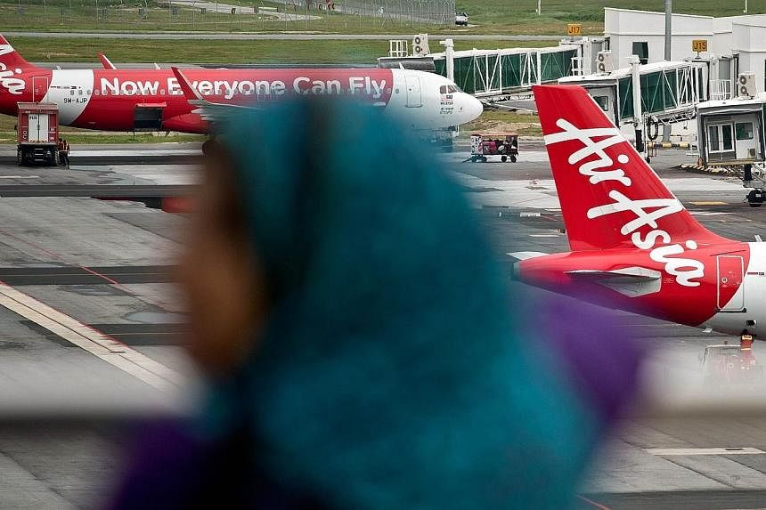 A Malaysian woman watches AirAsia Airbus A320 airplanes parked on the tarmac at the low-cost carrier Kuala Lumpur International Airport 2 (KLIA2) in Sepang on Dec 28, 2014. -- PHOTO: AFP