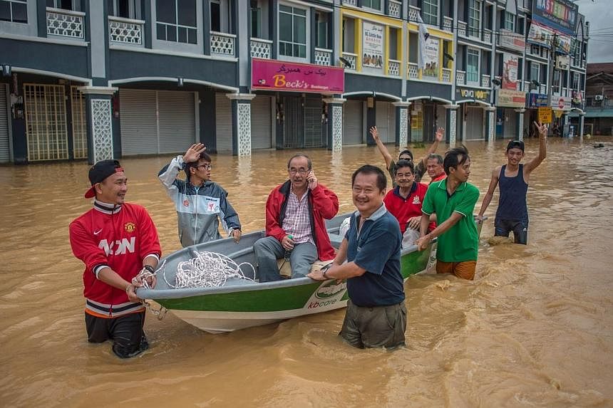 Local residents use a boat to cross floodwaters in Kota Bahru on Dec 28, 2014. -- PHOTO: REUTERS