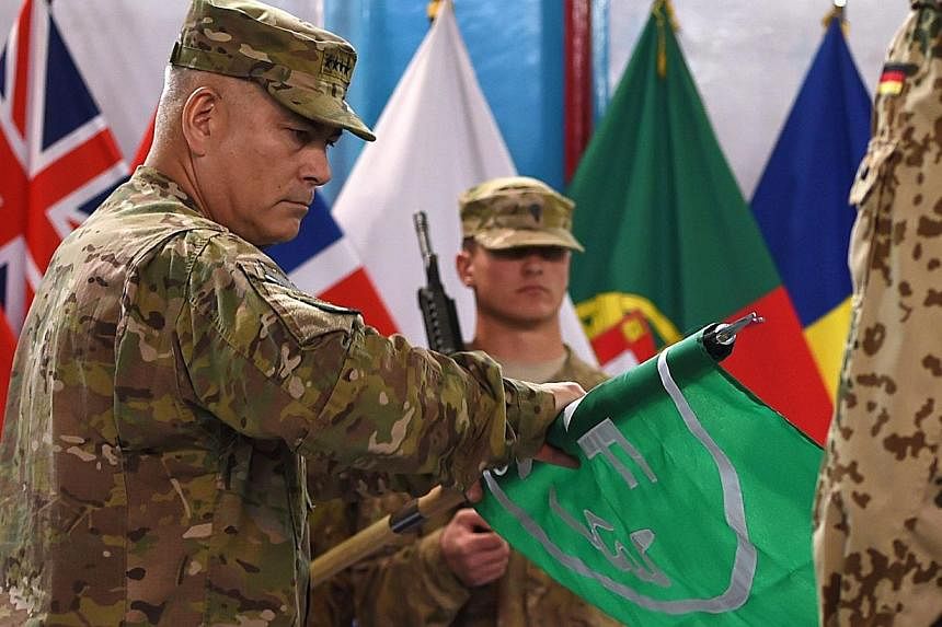 US General John Campbell (left) rolls the flag of the NATO-led International Security Assistance Force (ISAF) during a ceremony marking the end of ISAF's combat mission in Afghanistan at ISAF headquarters in Kabul on Dec 28, 2014.&nbsp;The US command