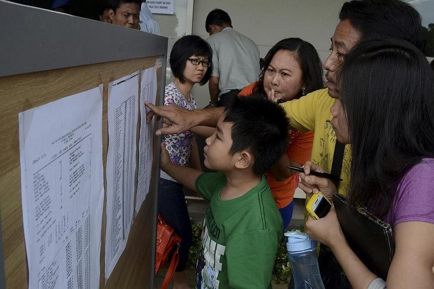 Family members of passengers on board AirAsia flight QZ 8501 look at a passenger list inside a crisis centre at Juanda Airport in Surabaya, East Java on Dec 28, 2014 in this photo taken by Antara Foto. -- PHOTO: REUTERS