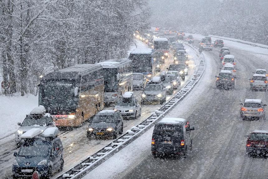 Snow falls as vehicles move bumper-to-bumper along the highway near Albertville, on Dec 27, 2014 as they make their way into the Tarentaise valley in the heart of the French Alps, home to many of the famous French ski resorts. Heavy snowfall in the F