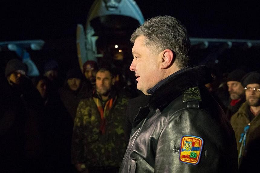 Ukrainian President Petro Poroshenko (right) welcomes Ukrainian troops freed from captivity after they arrive at an airport near Kiev early on Dec 27, 2014. -- PHOTO: AFP