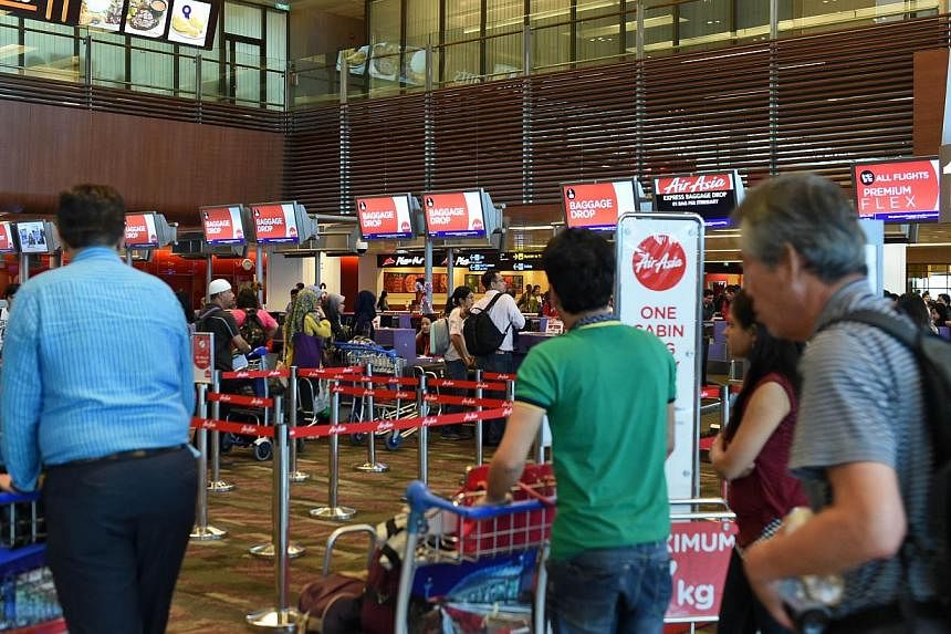 Passengers queue at the AirAsia check-in counter before their departure at Singapore Changi airport terminal on Dec 28, 2014. -- PHOTO: AFP