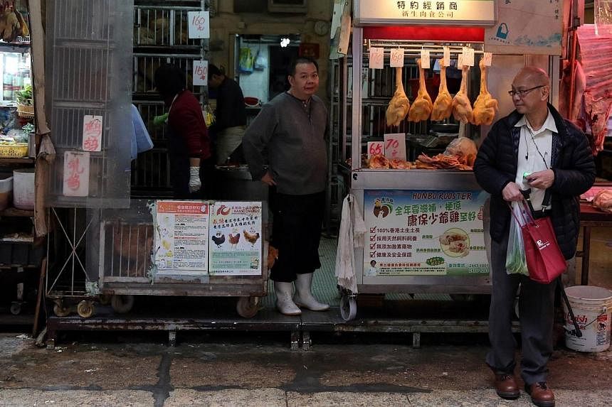 A worker (centre) sells live chickens at a shop in the Wan Chai district of Hong Kong on Dec 28, 2014.&nbsp;A man has died from the H7N9 bird flu strain in Zhejiang province, in eastern China, state media reported on Monday, Dec 29, 2014, at the end 