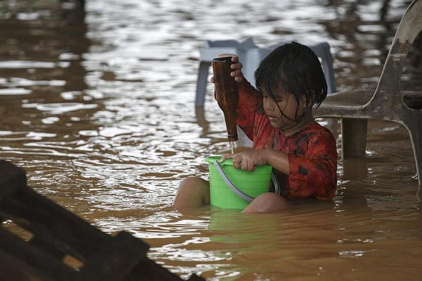 A girl plays on a flooded street on the outskirts of Kota Bharu in Kelantan on Dec 29, 2014.&nbsp;Flood relief efforts in Malaysia will be given a boost of $100,000 from the Singapore Government, revealed a statement from Singapore's Ministry of Fore