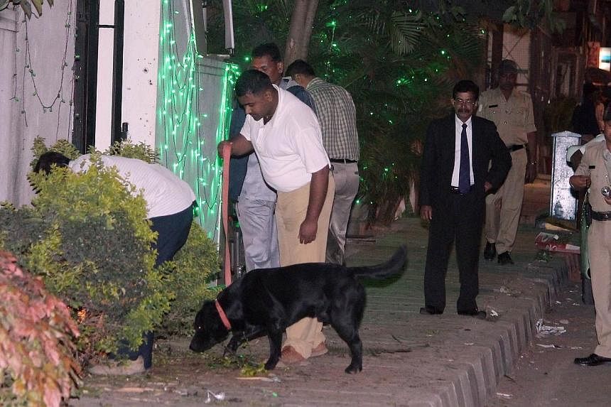 Bomb squad personnel along with sniffer dogs scour the blast site for evidence following a low intensity blast from an Improvised Explosive Device (IED). -- PHOTO: AFP