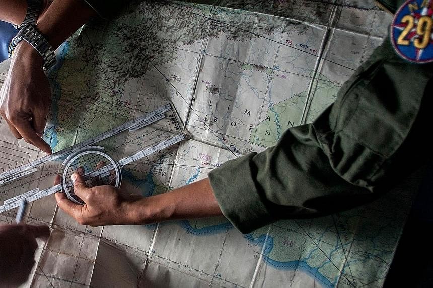 Indonesian Army personnel read a map during a search and rescue (SAR) operation for missing AirAsia flight QZ8501, over the waters of the Java Sea, on Dec 29, 2014. -- PHOTO: AFP