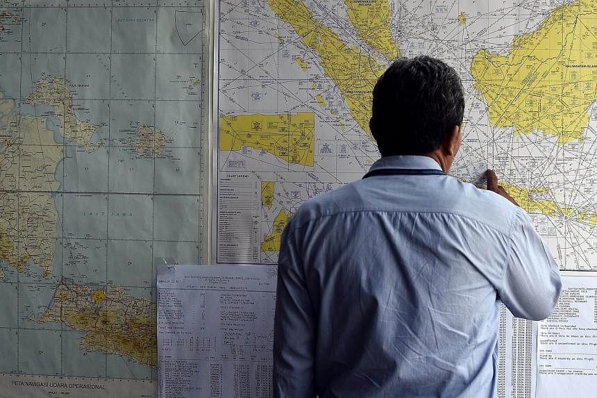 A man looks at a map showing the search area for the missing AirAsia flight QZ8501 outside the crisis centre set up at Juanda International Airport in Surabaya on Dec 29, 2014. -- PHOTO: AFP&nbsp;