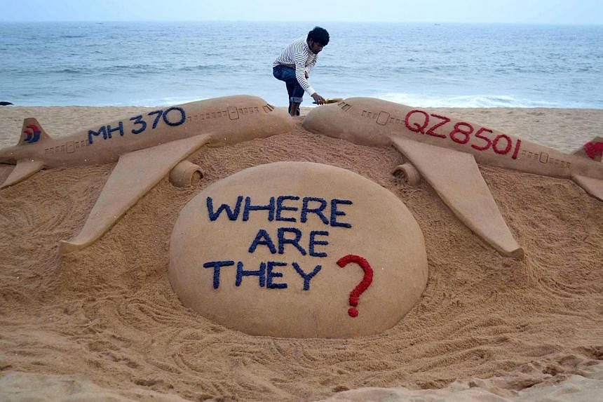 Indian sand artist Sudarsan Pattnaik giving the final touches to his sand sculpture portraying two missing aircraft, AirAsia QZ8501 and Malaysia Airlines MH370, on Golden Sea Beach at Puri, some 65km east of Bhubaneswar, on Dec 29, 2014. -- PHOTO: AF