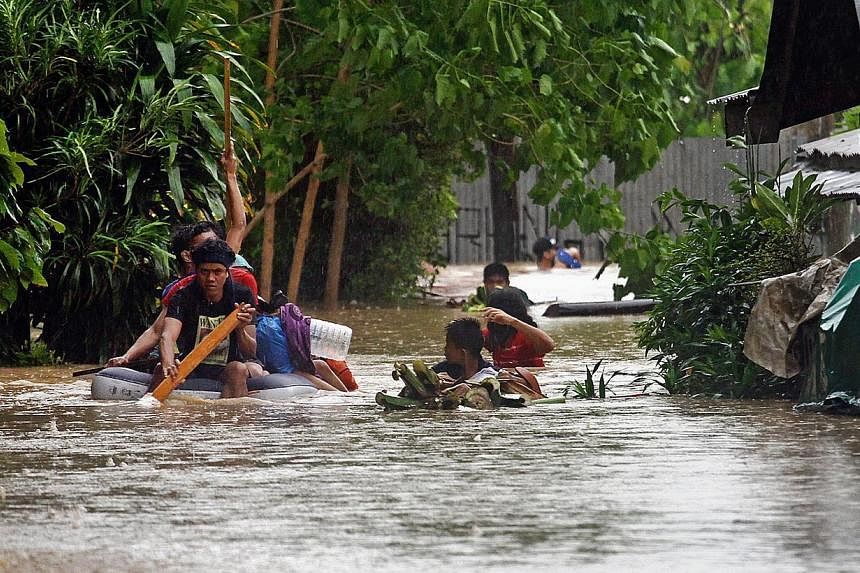 Residents help each other out from their inundated neighbourhoods after rains spawned by a tropical storm, locally known as Seniang, caused flooding in Misamis Oriental on the southern Philippine island of Mindanao on Dec 29, 2014. -- PHOTO: AFP